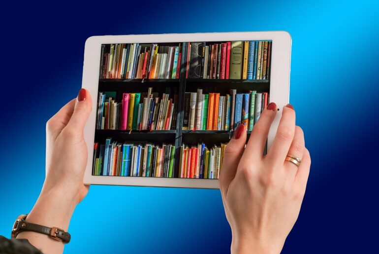 Person hält Tablet mit Büchern auf dem Display in der Hand