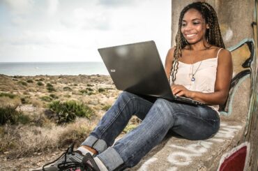 Frau arbeitet entspannt mit Laptop am Strand